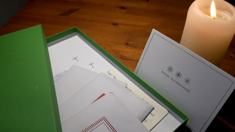 A paper box full of letters, with a Christmas card and a candle.
